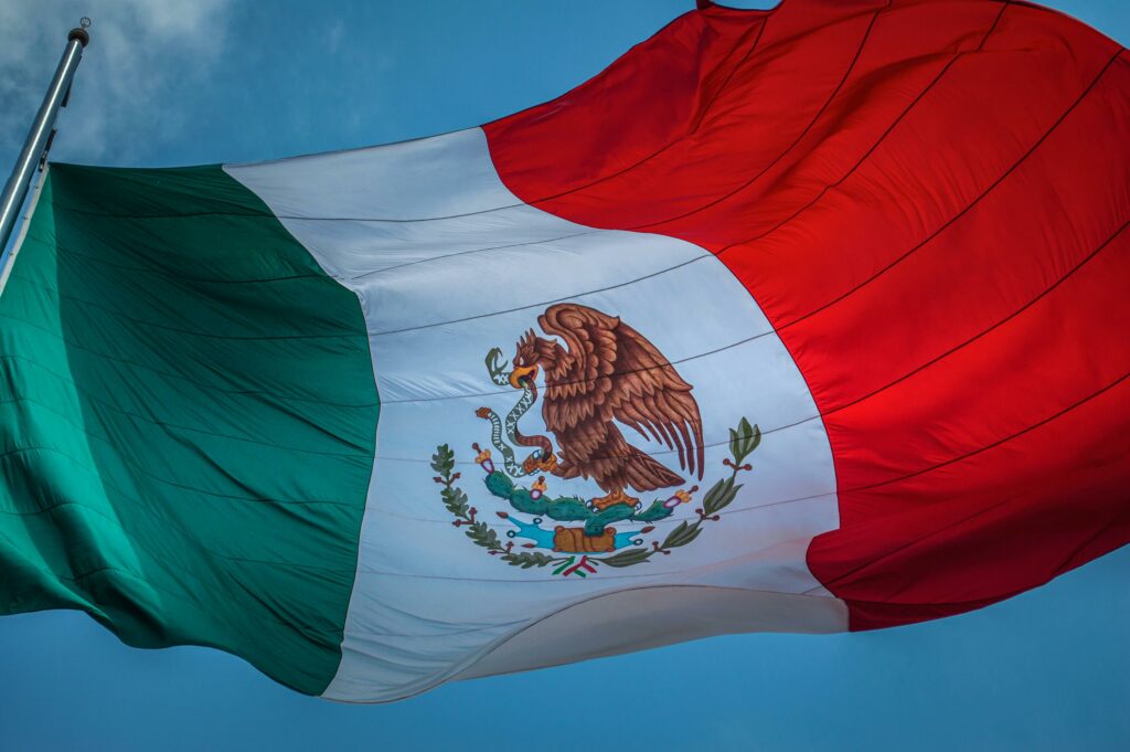 Drapeau mexicain flottant au vent, symbolisant la culture, l'histoire et l'unité du Mexique. S'expatrier et travailler au Mexique