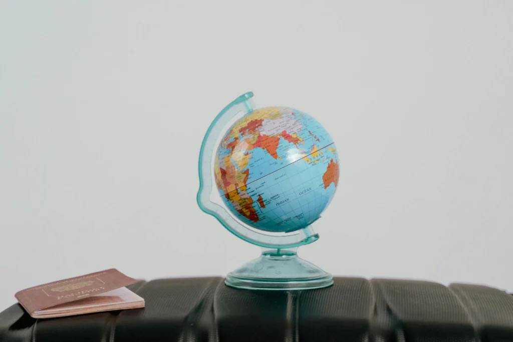 Un globe et un passeport posés (visa) sur une valise, symbolisant les démarches essentielles pour voyager ou s'installer à l'étranger